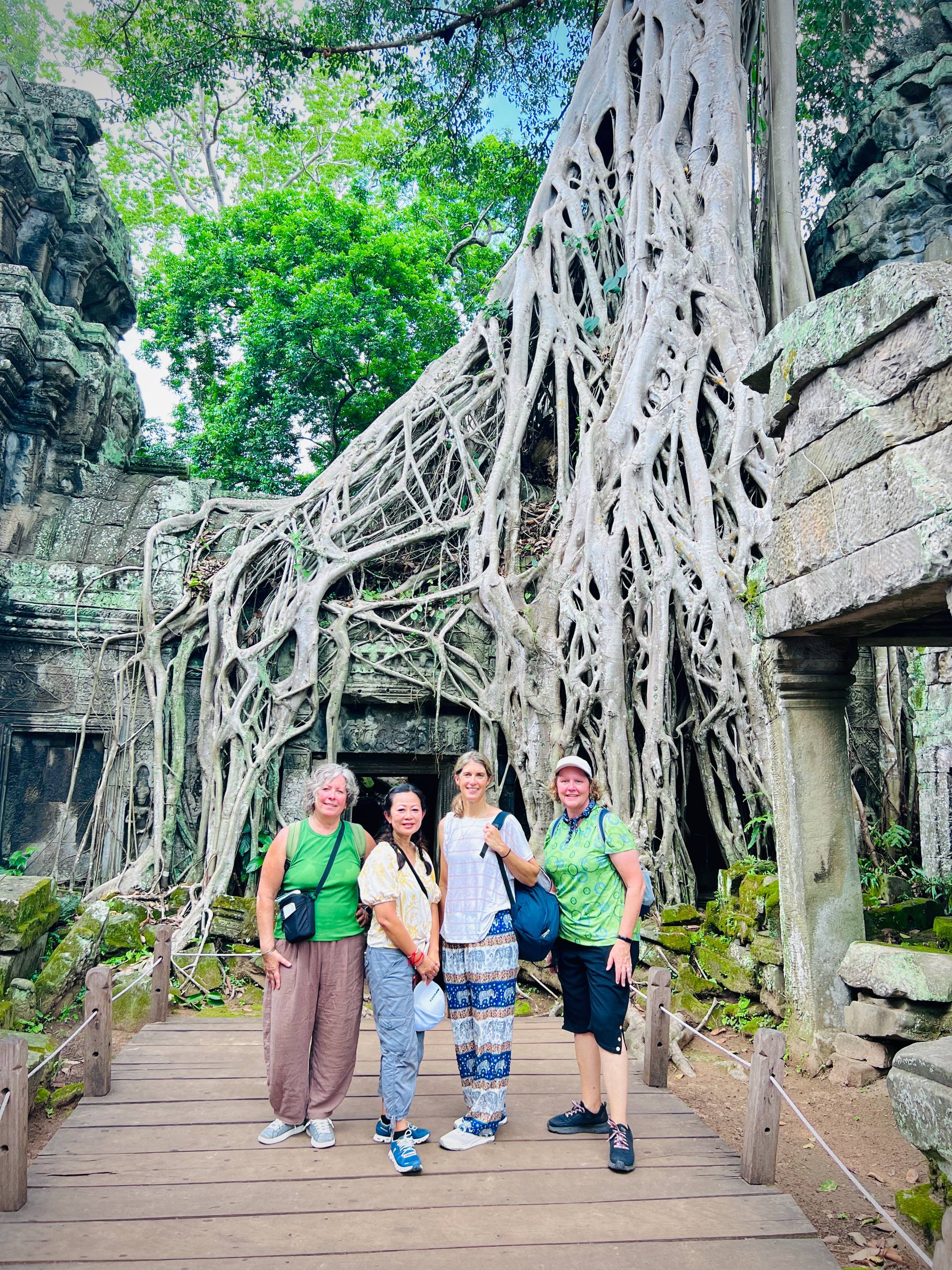 Visitors exploring the iconic tree roots at Ta Prohm Temple in Angkor Archaeological Park, Siem Reap, Cambodia.